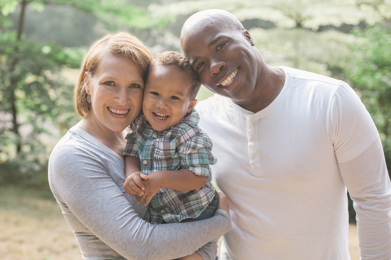 Mom, dad and toddler holding each other and smiling.